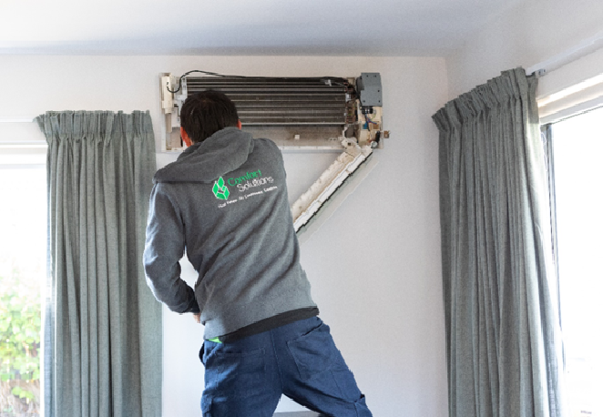 Technician servicing a heat pump system in an Auckland residence for optimal performance.